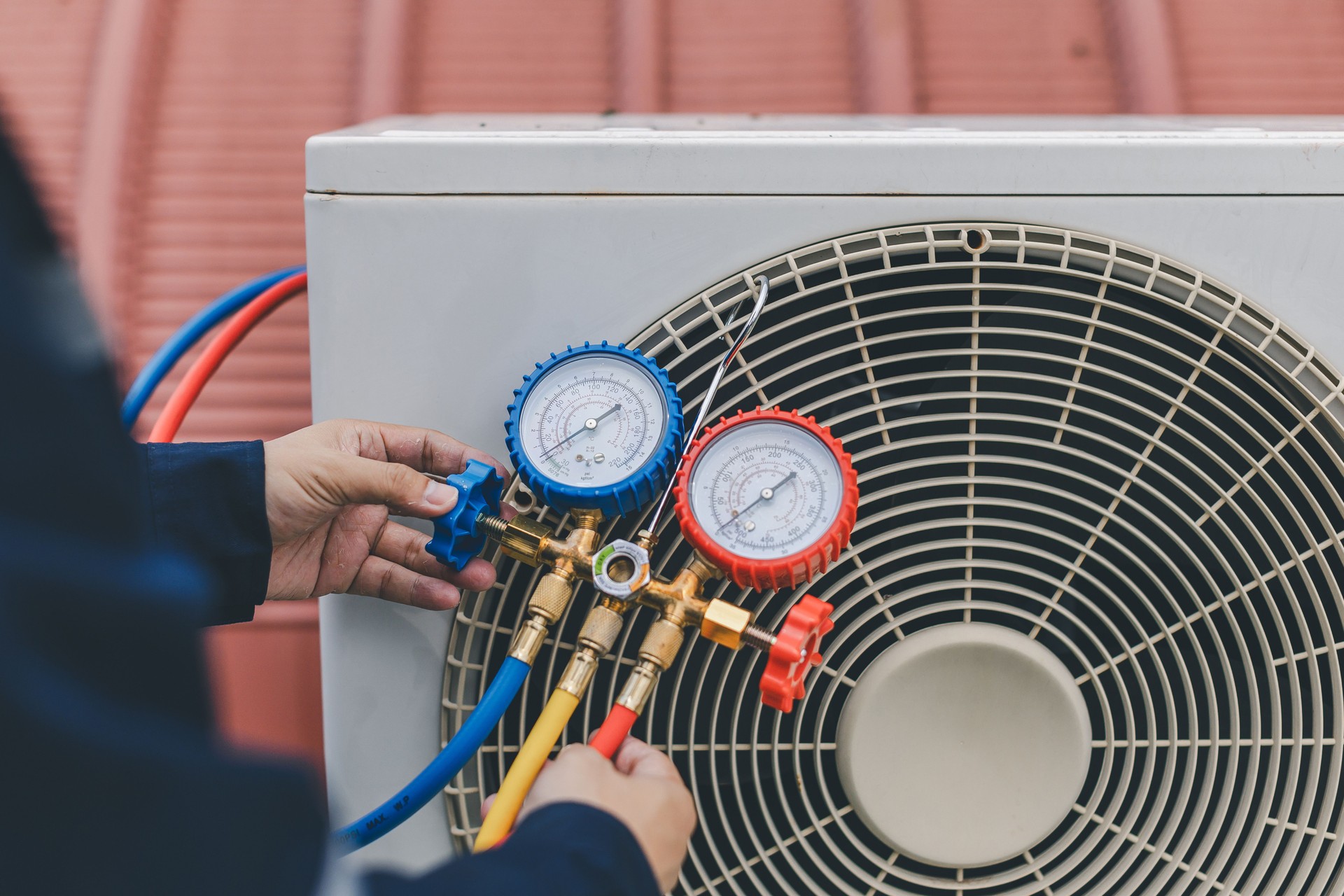 Technician is checking air conditioner. Air conditioning, HVAC service technician using gauges to check refrigerant and add refrigerant.